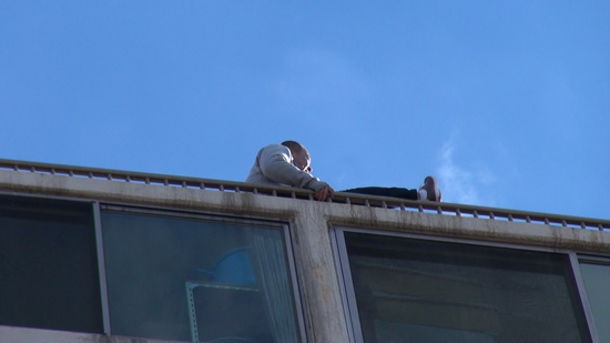 중국인 관광객 뤼모(43)씨가 제주시 연동 모 아파트 옥상 난간에 앉아 투신 소동을 벌이고 있다.